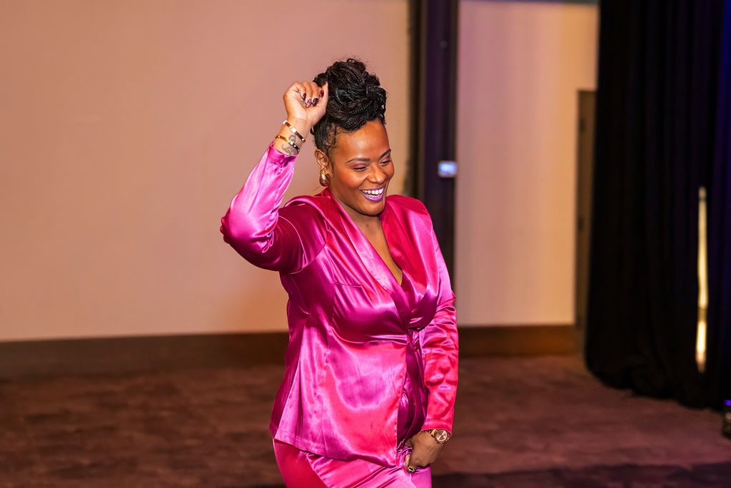 An attendee dancing under pink lighting at the Women of Work Gala